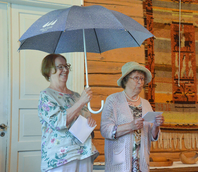 Kaksi naista esittää runoja sateenvarjon alla